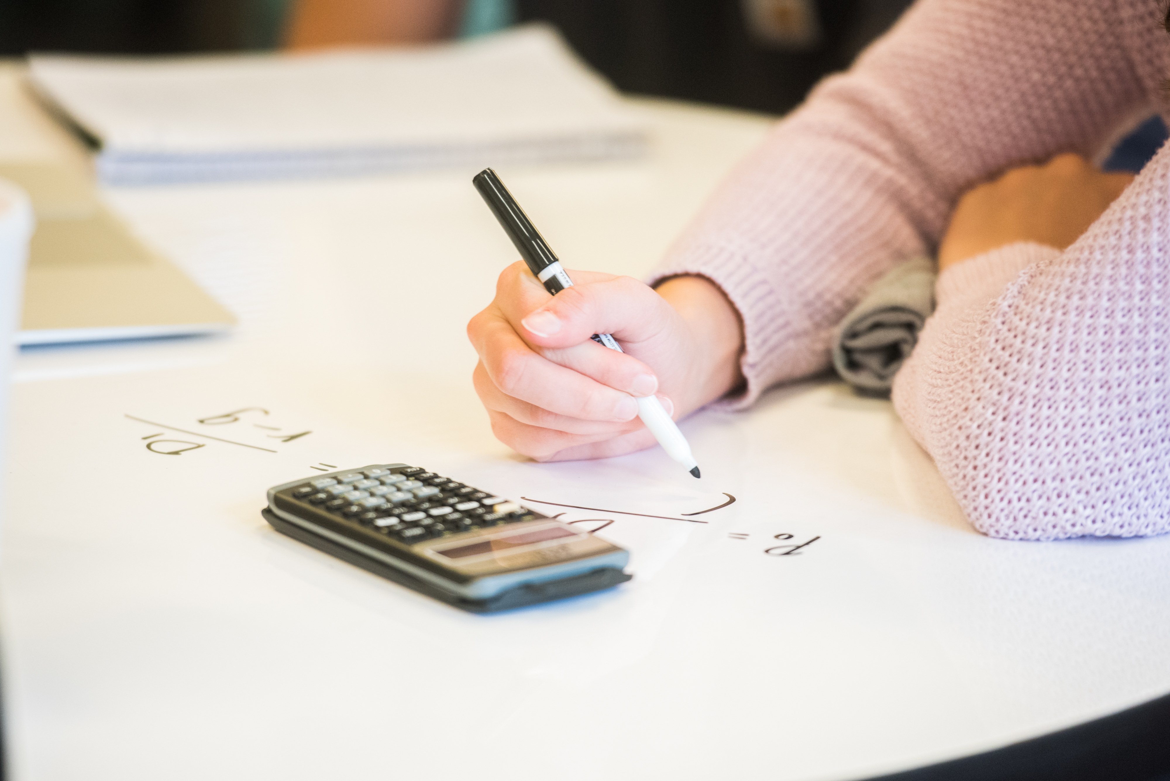 Student writing on whiteboard table