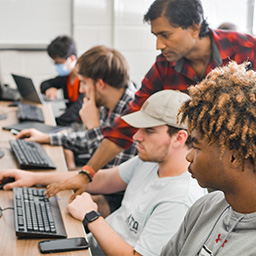 TROY professor working with students in a computer lab.