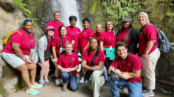 A group of Troy University students traveling abroad in front of a waterfall