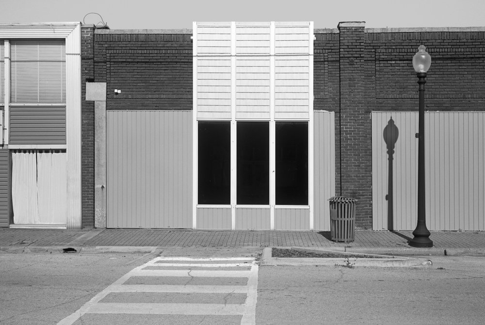 Black and white image of a street in Moundville. At the center there are three identical and symmetrical rectangle windows.