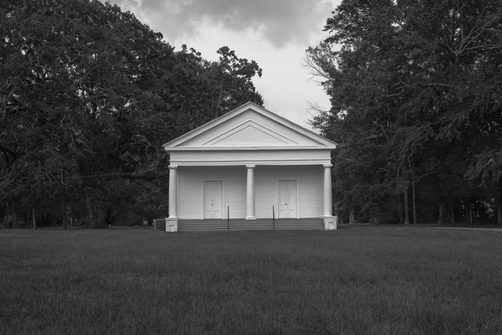 Black and white, symmetrical church centers the frame. There are identical doors on either side of the front.