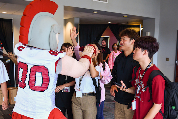 T-roy high fiving new international students who are checking in for orientation