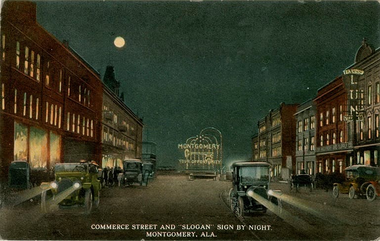 Color print of multi-story commercial buildings on Commerce Street in Montgomery, Alabama at night.