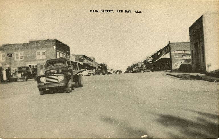 Black and white photograph of Red Bay, Alabama's Main Street showing commercial buildings with an old Ford pickup in the foreground.