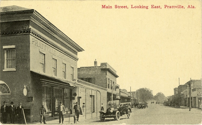 Black and white print of unpaved Main Street in Prattville, Alabama showing one and two-story commercial buildings.