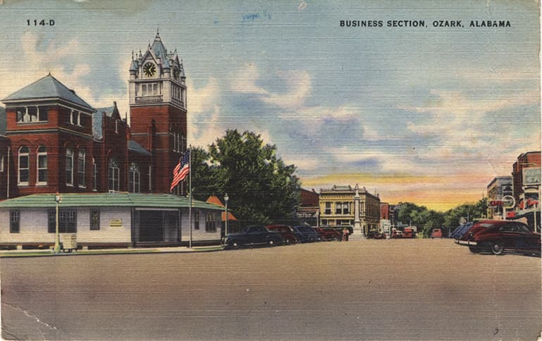 Color print of the business section in downtown, Ozark, Alabama showing the courthouse and several commercial buildings.