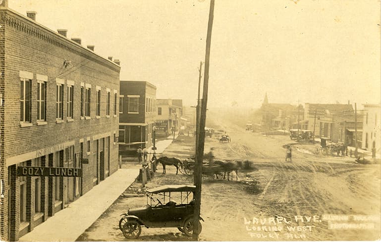 Black and white photograph of unpaved Laurel Avenue in Foley, Alabama showing one and two-story commercial buildings.