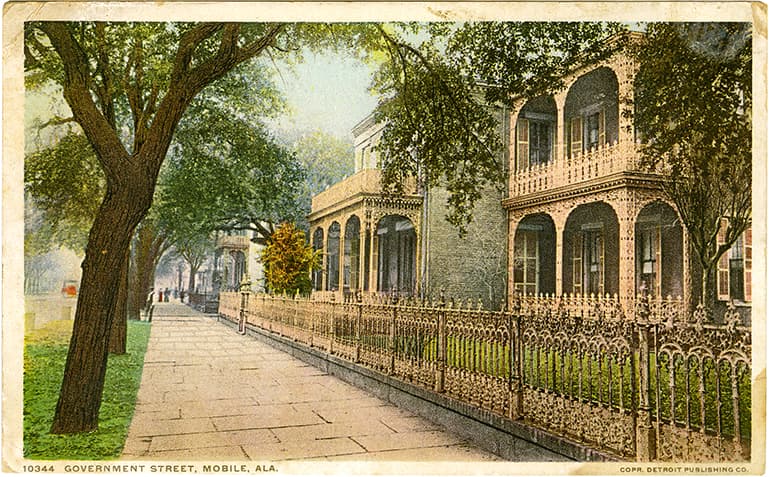 Color print of a residential section of Government Street in Mobile, Alabama showing two-story homes with wrought iron railings. Postmarked February 7, 1919. 