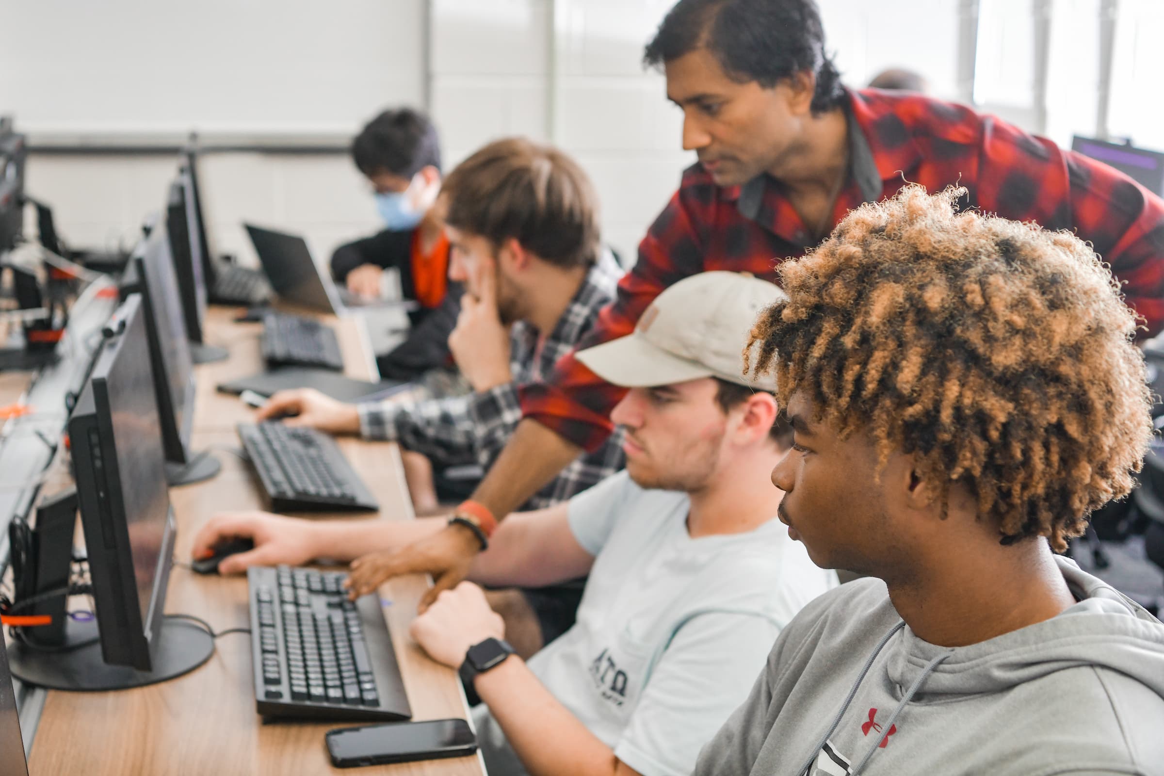 TROY students in a computer lab working with a professor.