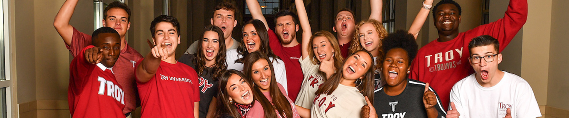 Students cheering at a TROY football game.