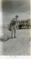 Photograph of soldier with duffel bags, wood-paneled automobile in background, dated 1949